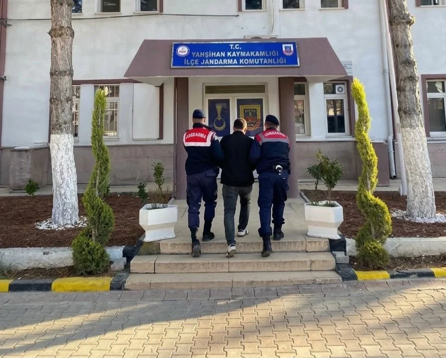 Jandarma ekiplerinin aranan kişiye eşlik ettiği görüntü. Jandarma personelinin bir kişiye Yahşihan İlçe Jandarma Komutanlığı binası önünde eşlik ettiği görüntü